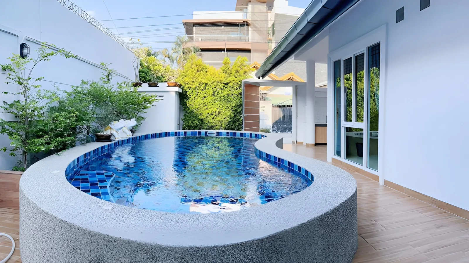 Curved private swimming pool and wood-effect terrace beside the villa at After Party Villas